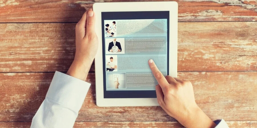 hands with tablet over wooden table showing blog articles