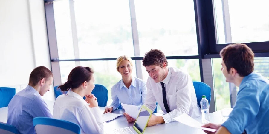 business meeting with 5 people with laptop and notes